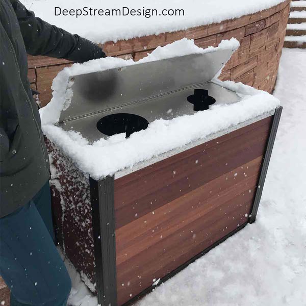 An Audubon double-stream 21-gallon modern wood Commercial combined Recycling and Trash Receptacle crafted with Ipe tropical hardwood and fitted with an optional 316 stainless steel weatherproof watertight lid shown at ski area keeping out the snow.