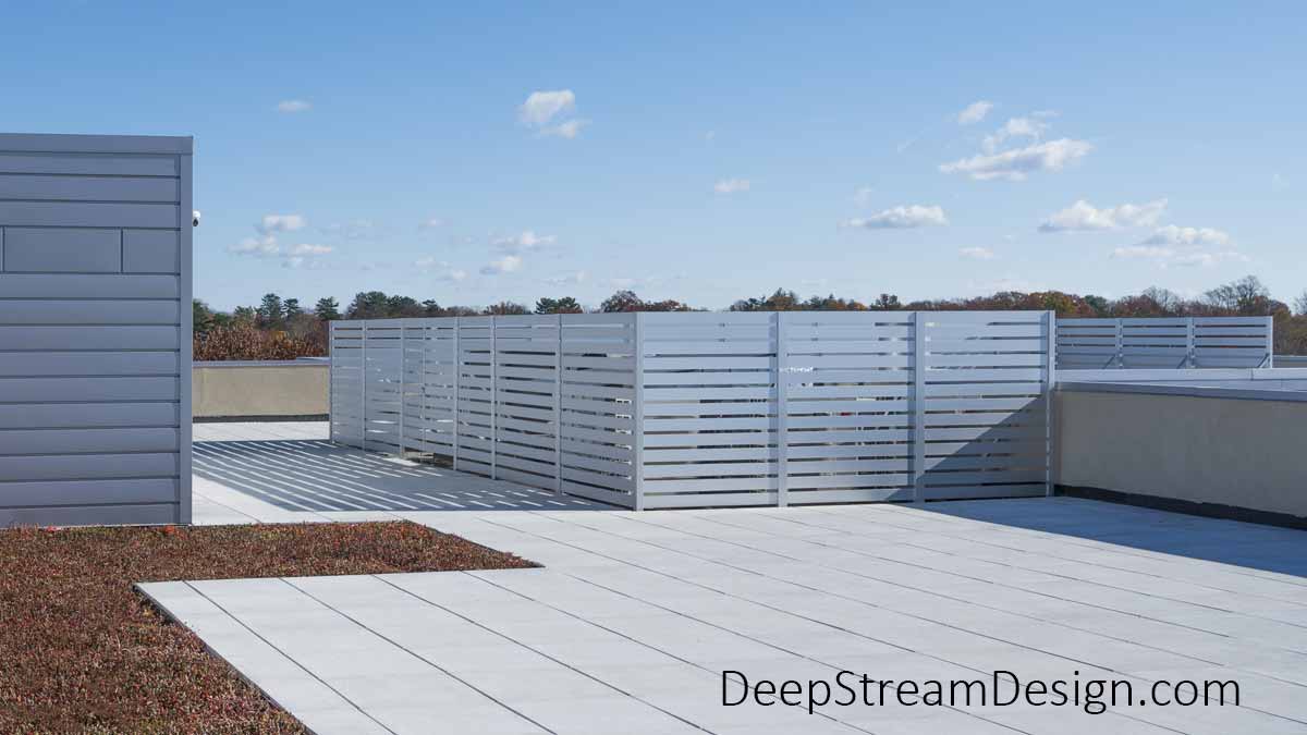 DeepStream's Modern Architectural Anodized Aluminum Screen Wall, with double opening gate, hides HVAC mechanical systems on this modern apartment building's roof deck, blending in seamlessly with the aluminum facade.