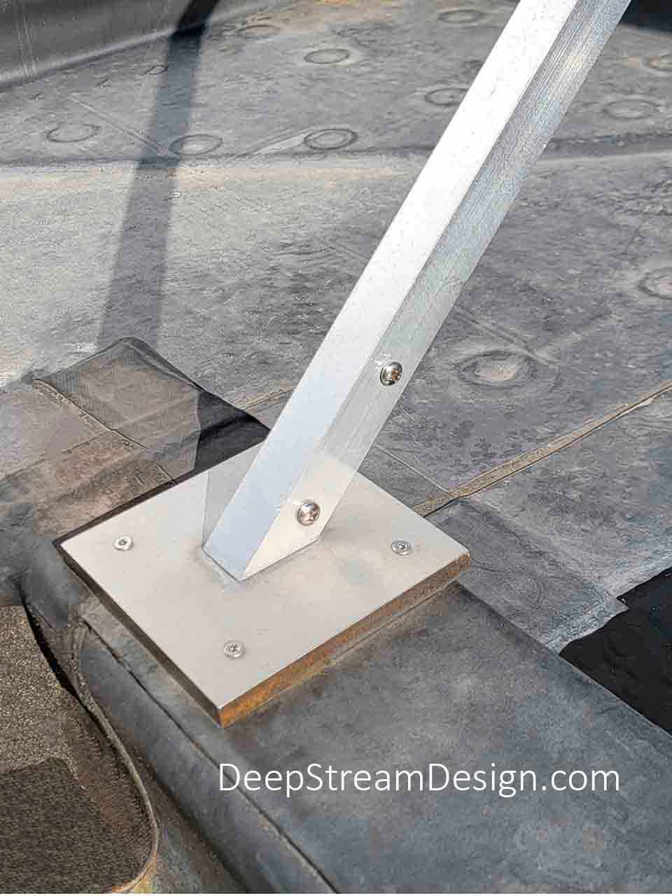 Rooftop photo showing the detail of a stainless steel foot pad anchoring the aluminum strut of a panel that makes up a Screen Wall enclosing Rooftop Mechanical Systems.